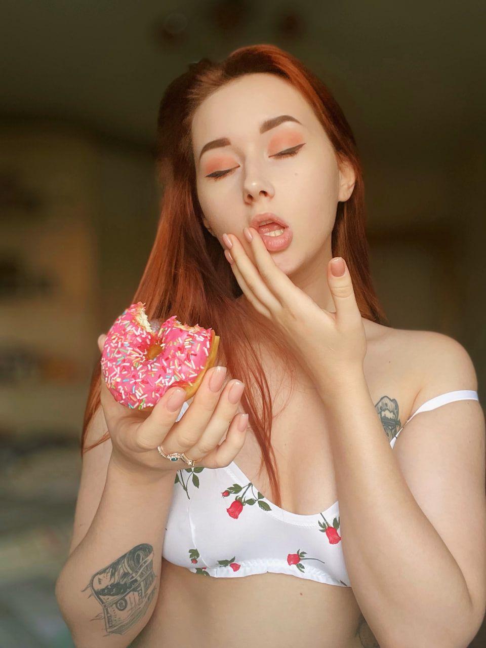 angel_rainbow_peach with their eyes closed wiping the corner of their mouth after having taken a bite of a pink donut